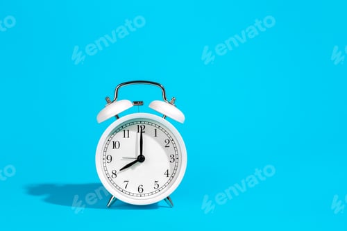 Preview: White alarm clock on a blue background isolated, close-up.
