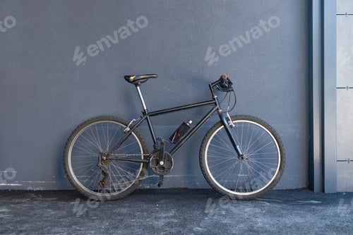 Preview: Bicycle leaning against a gray wall with copy space. Side view.