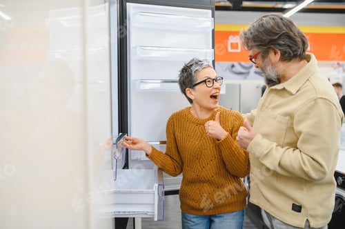 Preview: Mature couple shopping for new refrigerator showing satisfaction