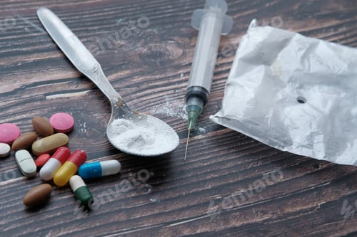 Preview: Drug syringe and cooked heroin on spoon, top view