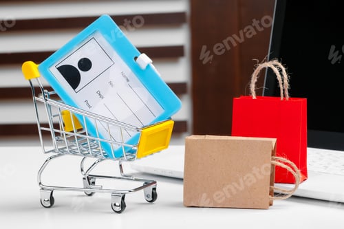 Preview: Online shopping concept. Shopping cart, laptop on the desk