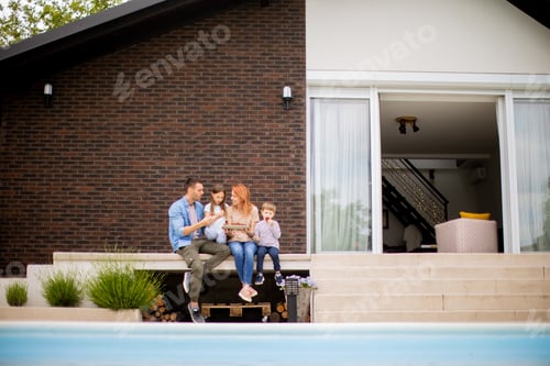 Preview: Family with a mother, father, son and daughter sitting outside on steps