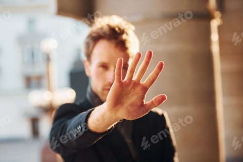 Preview: Shows stop gesture by the hand. Elegant young man in formal classy clothes outdoors in the city