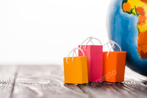 Preview: colorful toy shopping bags near globe on table isolated on white, e-commerce concept