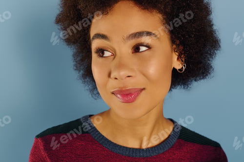 Preview: Emotional portrait of a young woman with curly hair expressing deep feelings against a blue backdrop