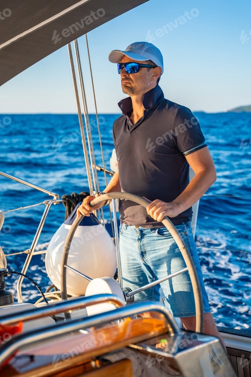 Preview: Young man captain stands at the helm and controls a sailboat during a journey by sea