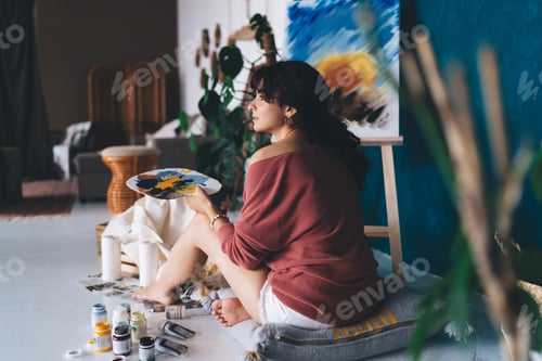 Preview: Attractive young female artist draws picture with paints and enjoys relaxing process of her hobby