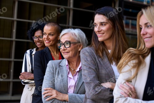 Preview: Side view. Group smiling empowered diverse formal business women standing with arms crossed outdoor.