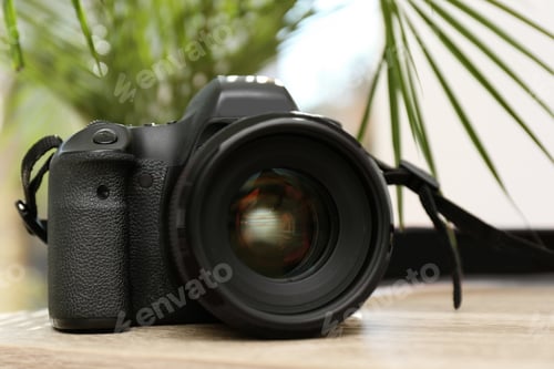 Preview: Professional camera on table against blurred background. Photographer's equipment