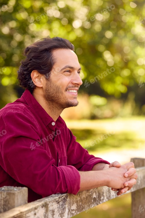 Preview: Portrait Of Smiling Casually Dressed Mature Man Leaning On Fence On Walk In Countryside