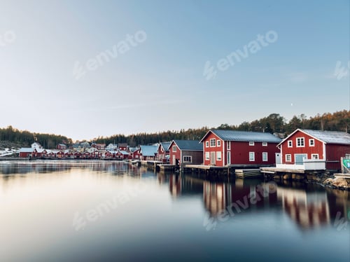 Preview: Beautiful view of wooden red houses near a lake with reflection in the water in Bonhamn, Sweden