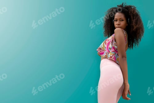Preview: beautiful young afro woman with headphones standing posing on an aquamarine blue background