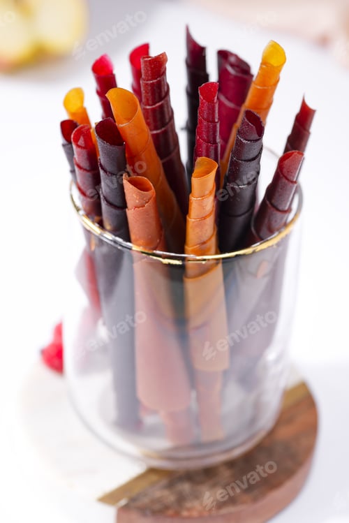 Preview: Colorful fruit leather rolls on a glass on light background