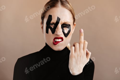 Preview: Woman with ponytail dressed in black sweater shows middle finger. Closeup portrait of angry girl wi