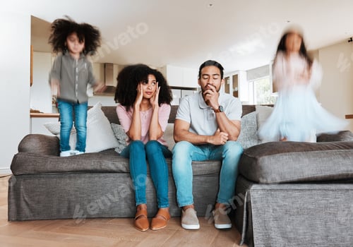 Preview: Children jumping with stressed parents on the sofa to relax in the living room of their house. Upse