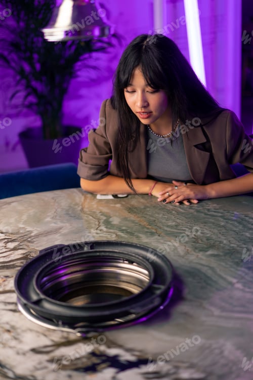 Preview: a young beautiful girl looks at the hood with a grill in a Korean restaurant before cooking