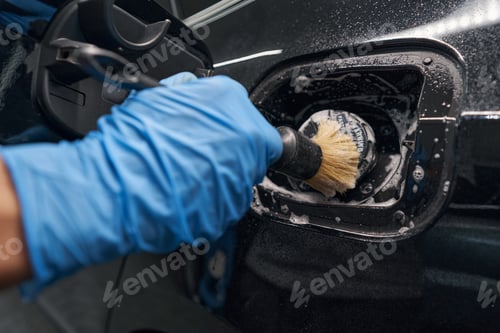 Preview: Automotive industry worker carefully detailing car body