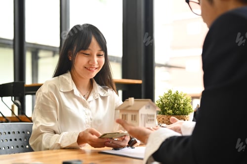 Preview: Happy female client making sale purchase, signing contract with real estate agent.