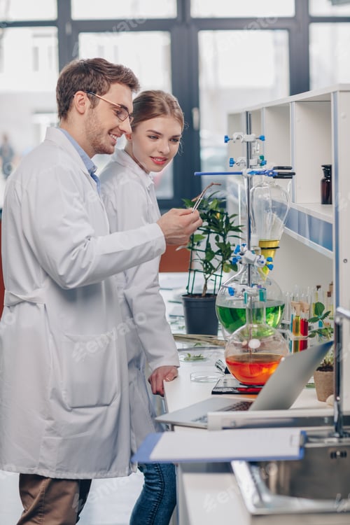 Preview: biologists in white coats working with flasks, reagents and lemon plant in laboratory