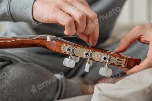 Preview: Changing strings on an acoustic guitar, male hands.