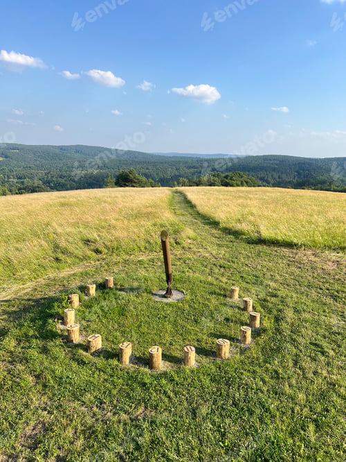 Preview: A sundial made of wooden bars in a field among greenery with a beautiful view