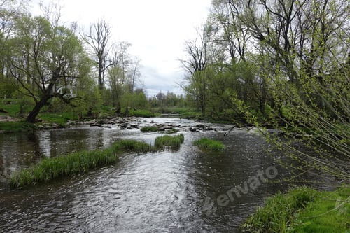 Preview: Serene river flows through lush greenery under a cloudy sky