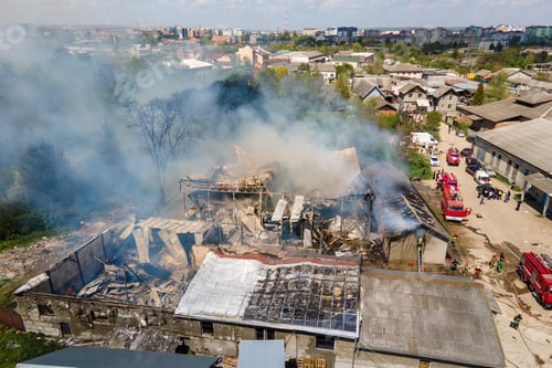 Preview: Aerial view of firefighters extinguishing ruined building on fire with collapsed roof and rising