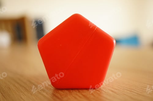 Preview: Shallow focus shot of a red pentagon shape plastic toy block with a blurred background