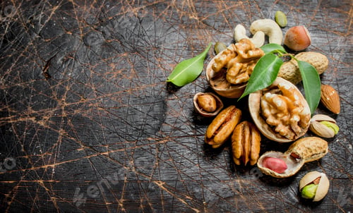 Preview: Nuts background. Assortment of different nuts with green leaves .