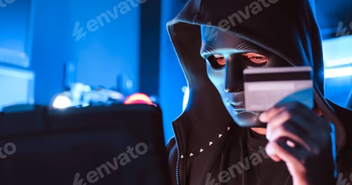 Preview: A hacker wearing a mask to cover his face is using computer to hack data to get ransom from victims.