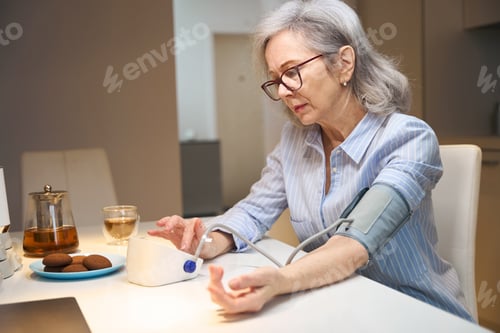 Preview: Worried elderly lady measures her blood pressure with a tonometer
