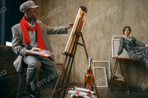 Preview: Happy painter draws female model in art studio