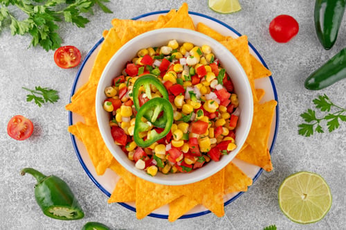 Preview: Corn salsa in a bowl with lime, jalapeno pepper, fresh herbs and tortilla chips. Healthy food