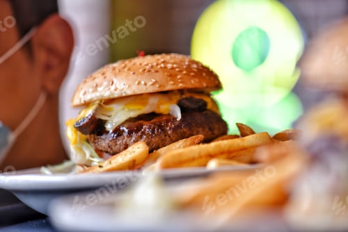 Preview: Server wearing ppe face mask at restaurant serving customer a delicious flame grilled cheeseburger