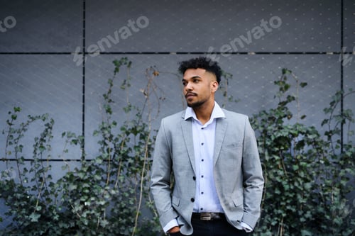 Preview: Portrait of young man student standing outdoors in city, hands in pockets