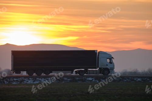 Preview: Semi-truck with cargo trailer driving on highway hauling goods in evening.