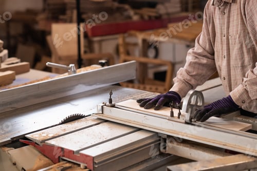 Preview: Woodworker using circular saw, cutting piece of wood at carpentry workshop.