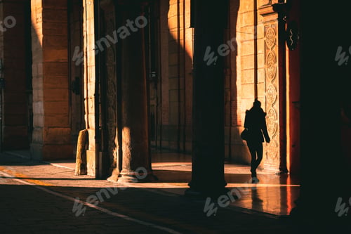 Preview: Woman walking in the shadows in the historic town of Bologna, Italy