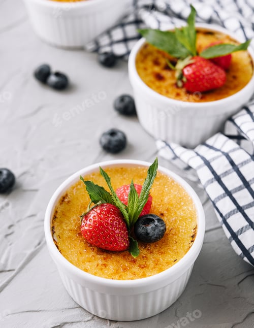 Preview: cup of creme brulee with dessert plug and mint leave with berries