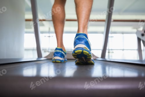 Preview: Rear view low section of a man running on treadmill in the gym