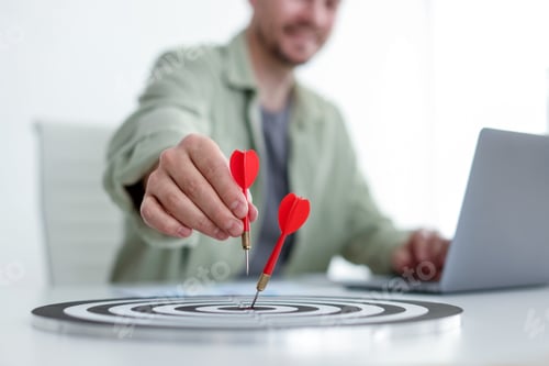 Preview: Man with dart aiming at dartboard while working indoors, closeup