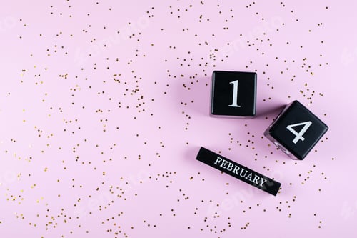 Preview: Valentines day greeting card. Flat lay with wooden block calendar 14 February and golden confetti