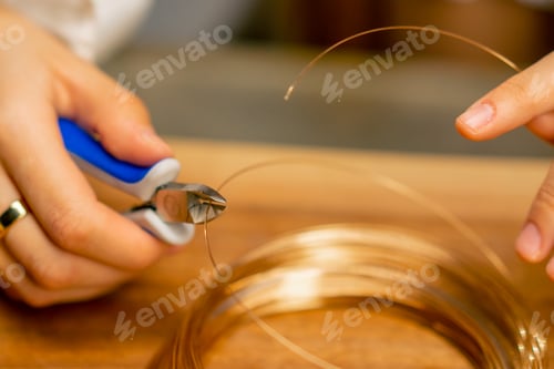 Preview: close-up hands of a young girl makes jewelry with her own hands cuts the remnants of wire necklace