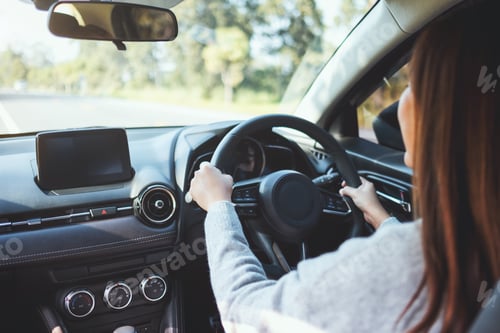 Preview: Closeup image of a woman holding steering wheel while driving a car on the road
