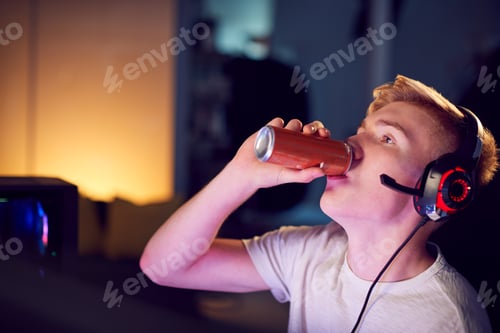 Young Man Drinks Beverage While Gaming at Home