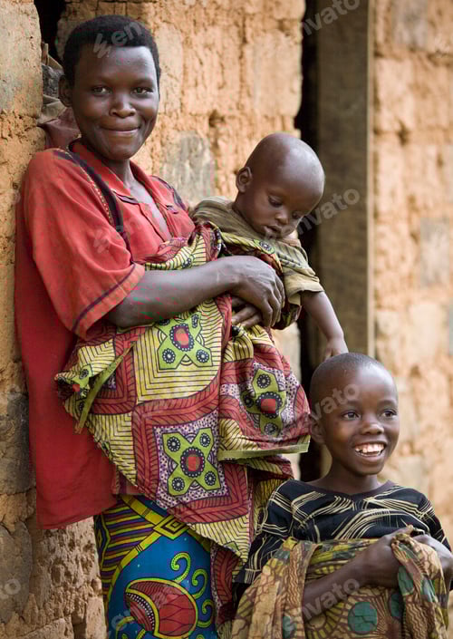 Preview: A mother's warmth Woman with children smiling beside a mudbrick home.