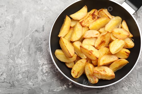Preview: Tasty baked potatoes in frying pan on grey textured table, top view. Space for text