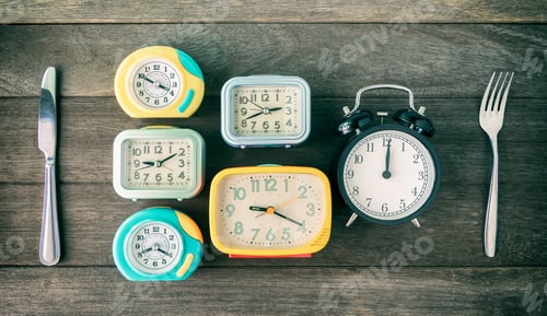 Preview: Colorful Alarm Clocks with Silverware on Wooden Surface