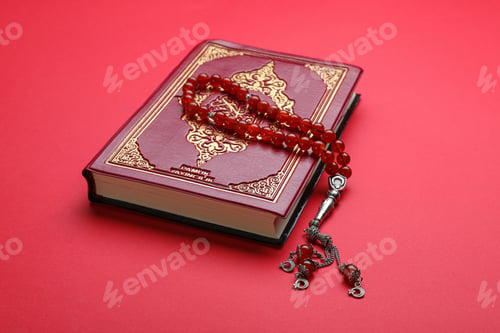 Preview: Muslim prayer beads and Quran on red background