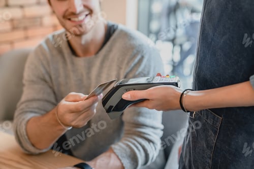 Preview: Selective focuse shot of swiping machine with credit card and a man paying